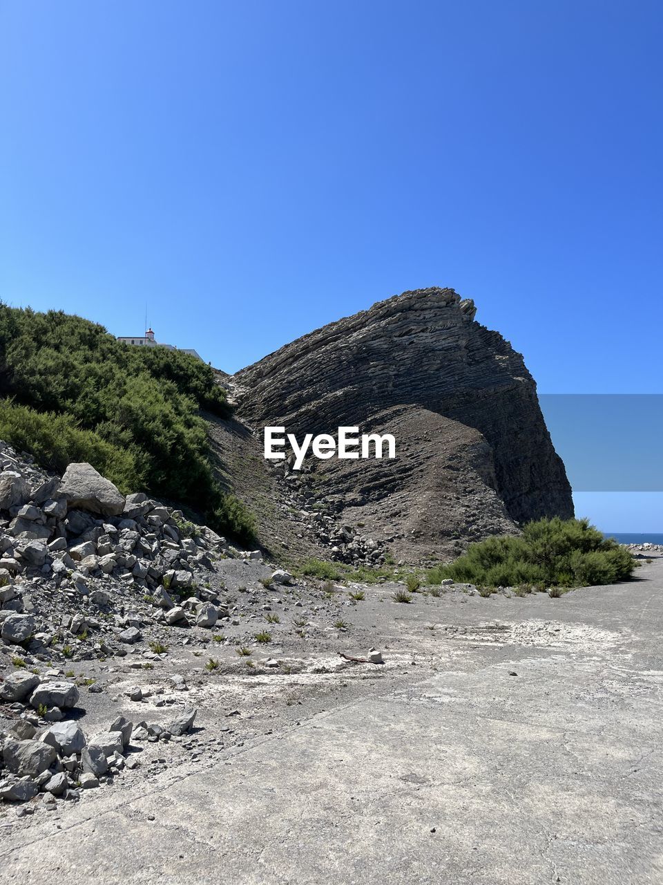 rock, sky, cliff, nature, blue, clear sky, no people, terrain, mountain, day, outdoors, plant, architecture, low angle view, scenics - nature, beauty in nature, land, tree, adventure, travel destinations, sunny, sunlight, travel, rock formation, history, tranquility, geology, built structure, mountain range, non-urban scene