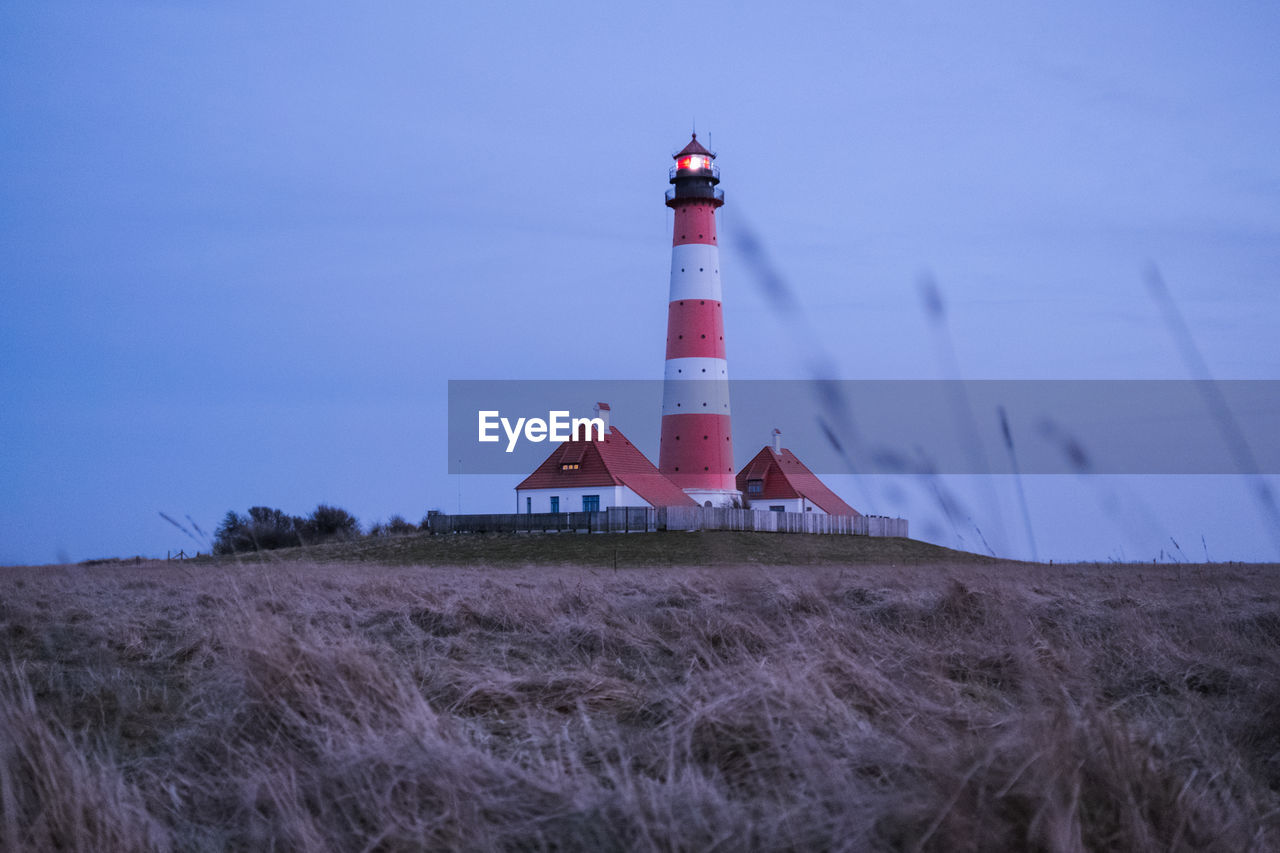 LIGHTHOUSE AMIDST FIELD AGAINST SKY