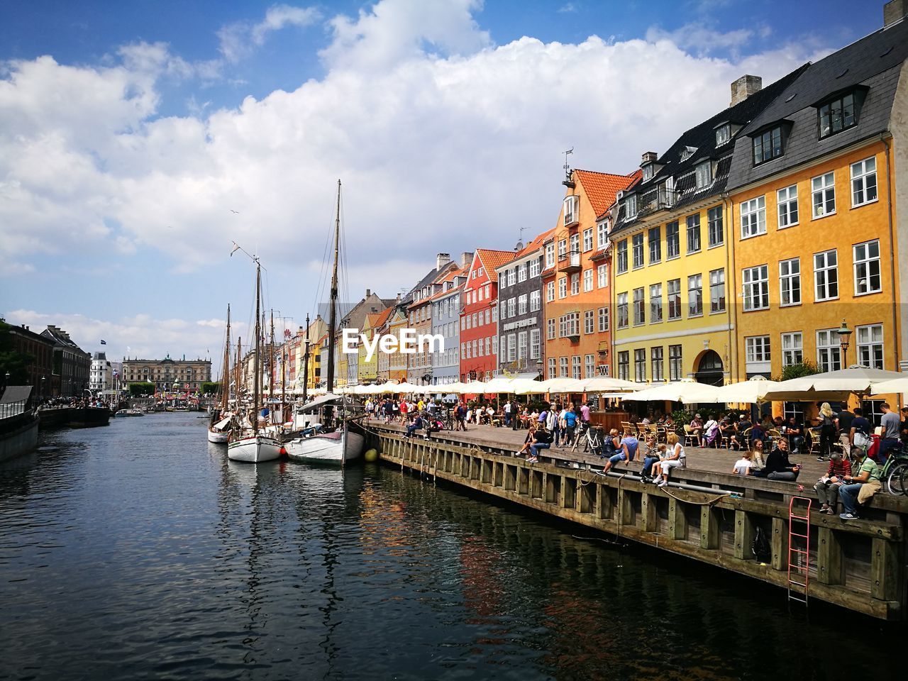 BOATS IN RIVER BY BUILDINGS AGAINST SKY