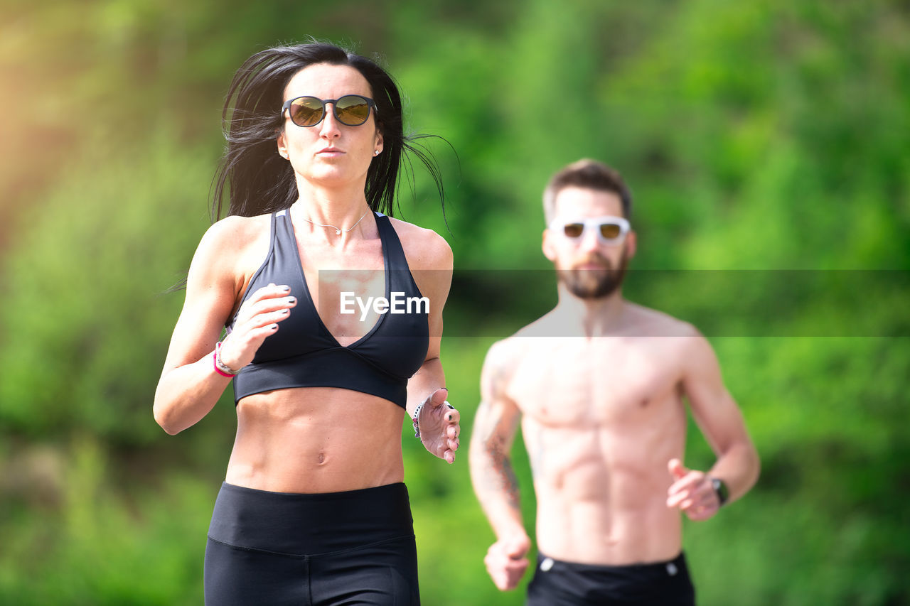 Couple wearing sunglasses running outdoors