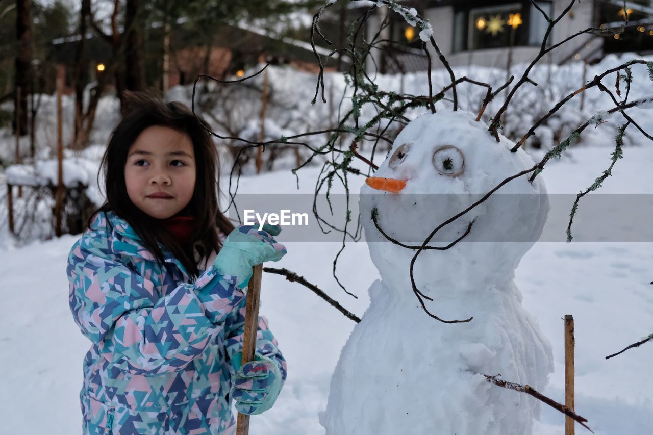 Portrait of girl by snowman
