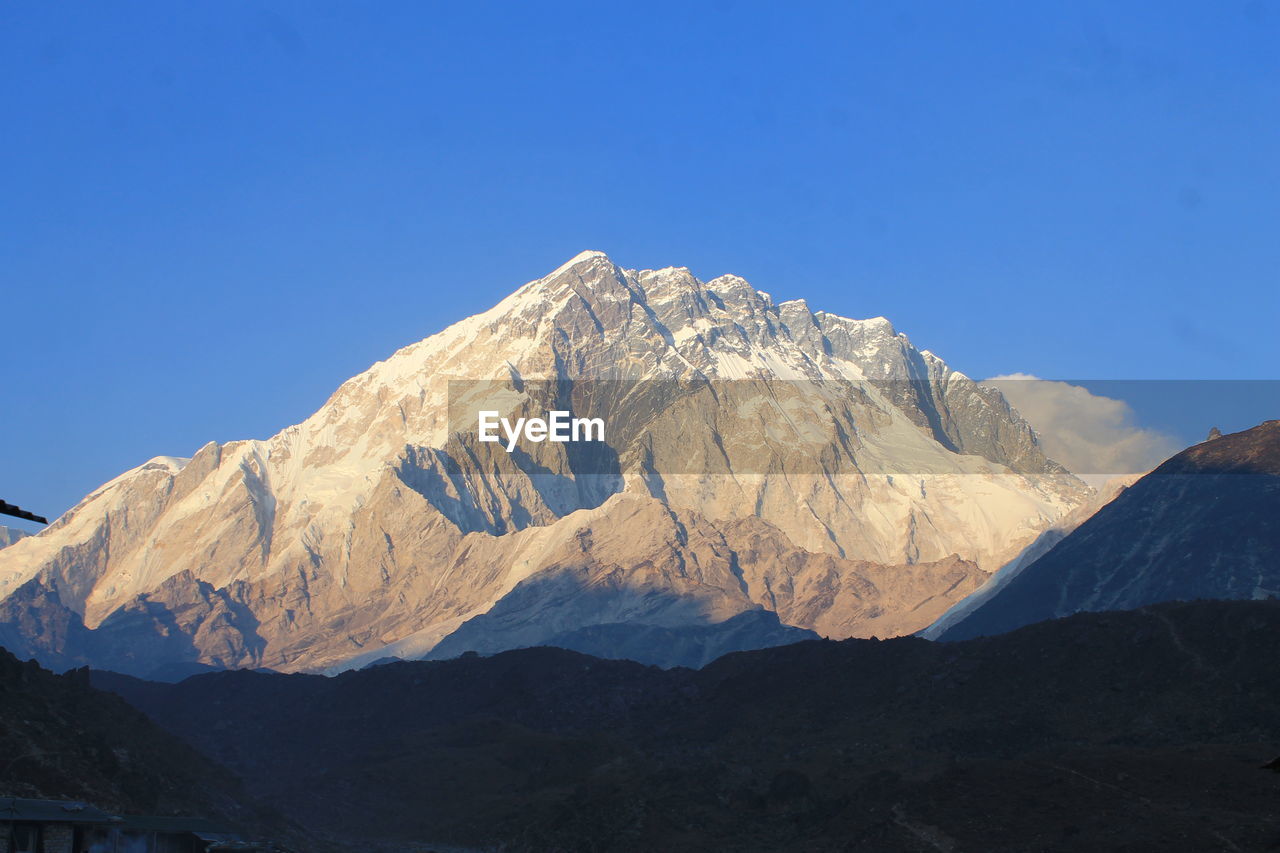 Scenic view of snowcapped mountains against clear blue sky