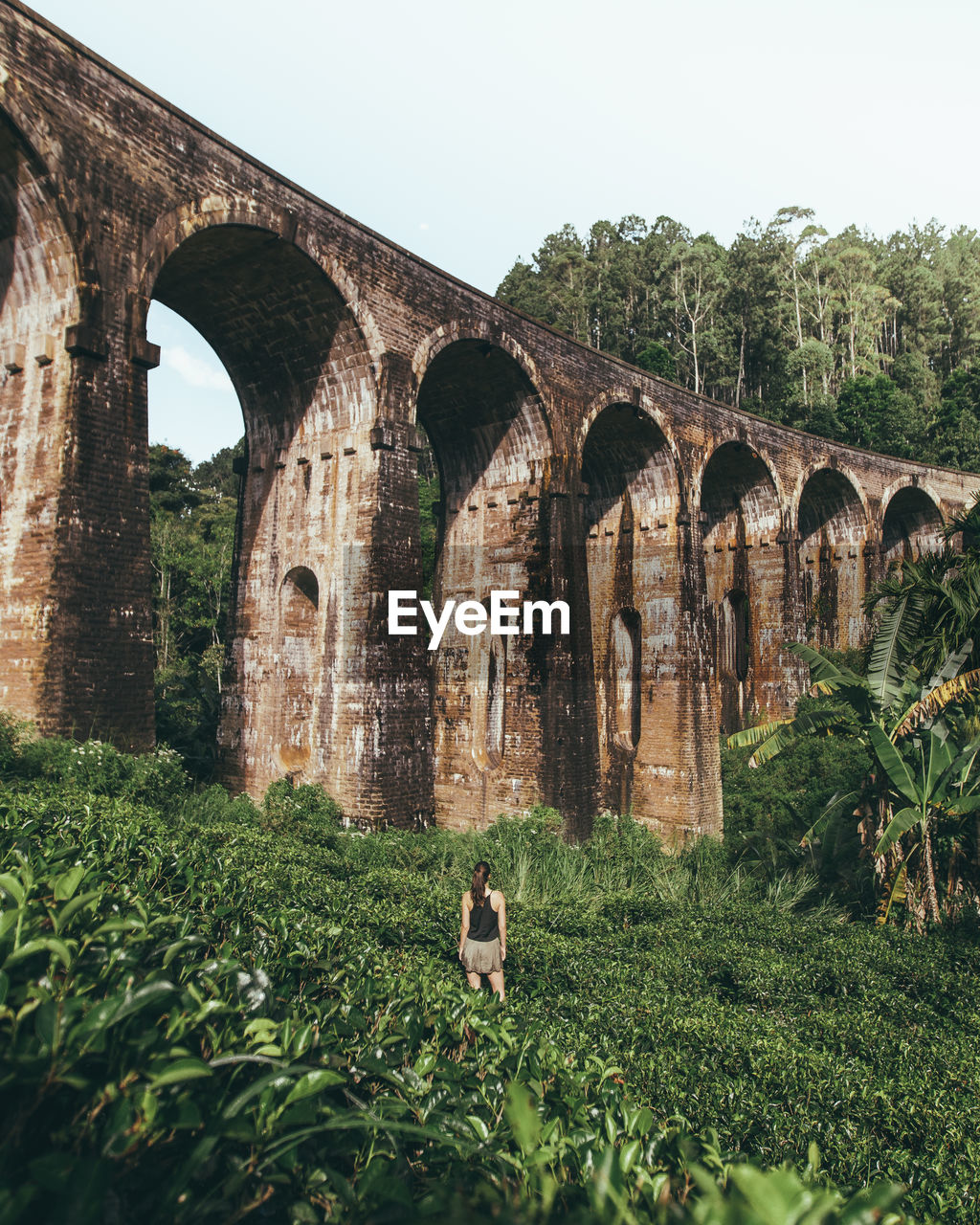 Rear view of woman standing against viaduct