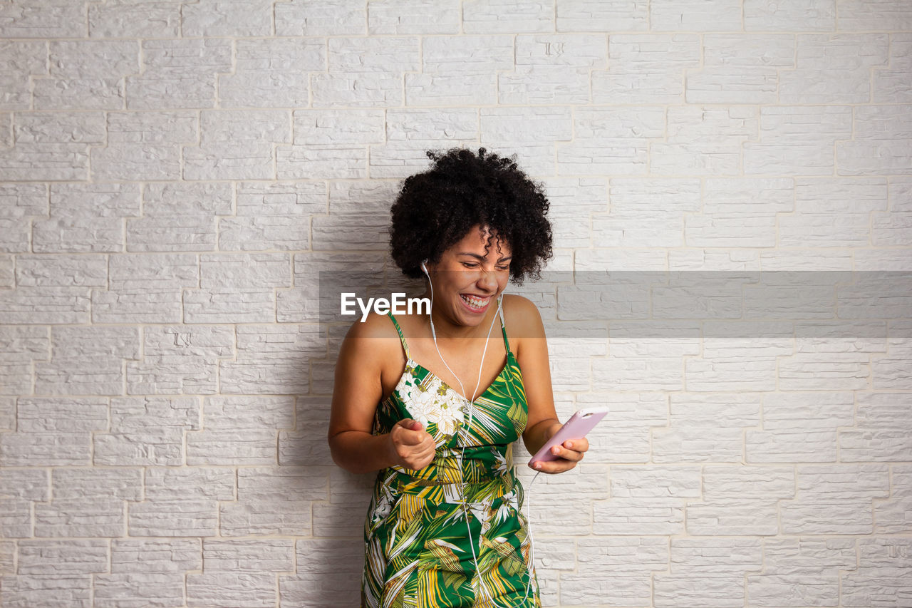 portrait of smiling young woman standing against wall