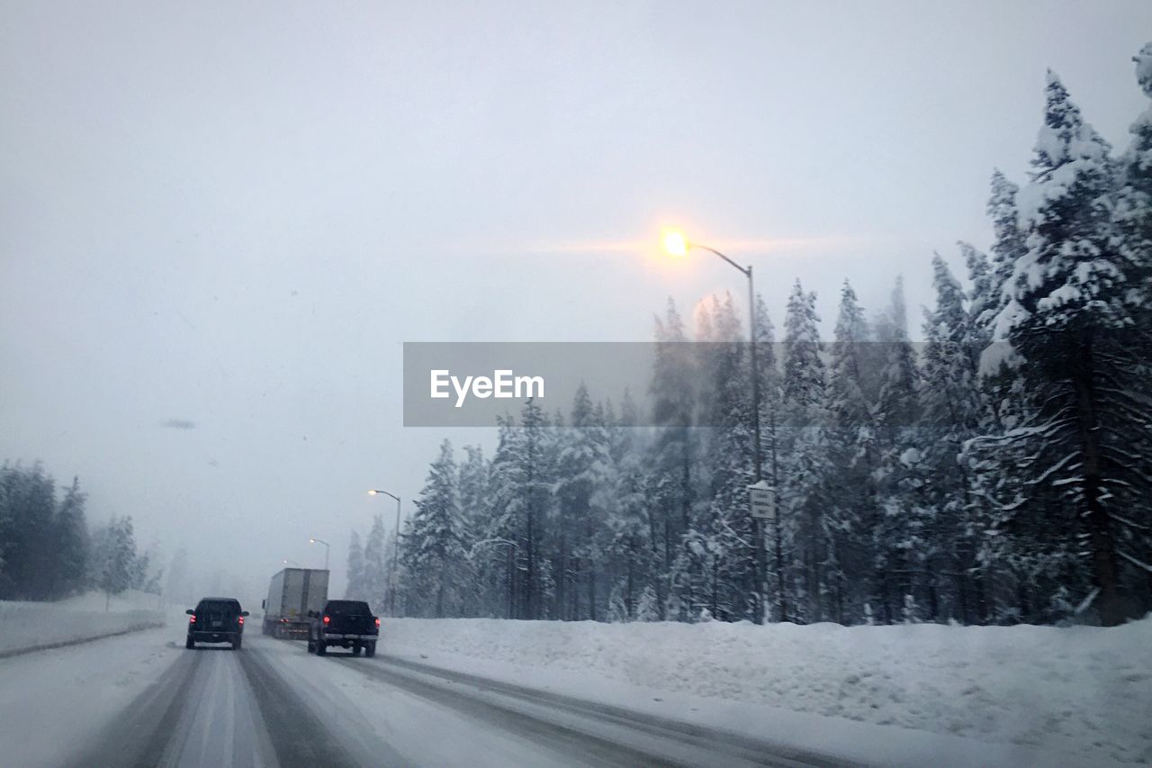 SNOW COVERED ROAD PASSING THROUGH LANDSCAPE