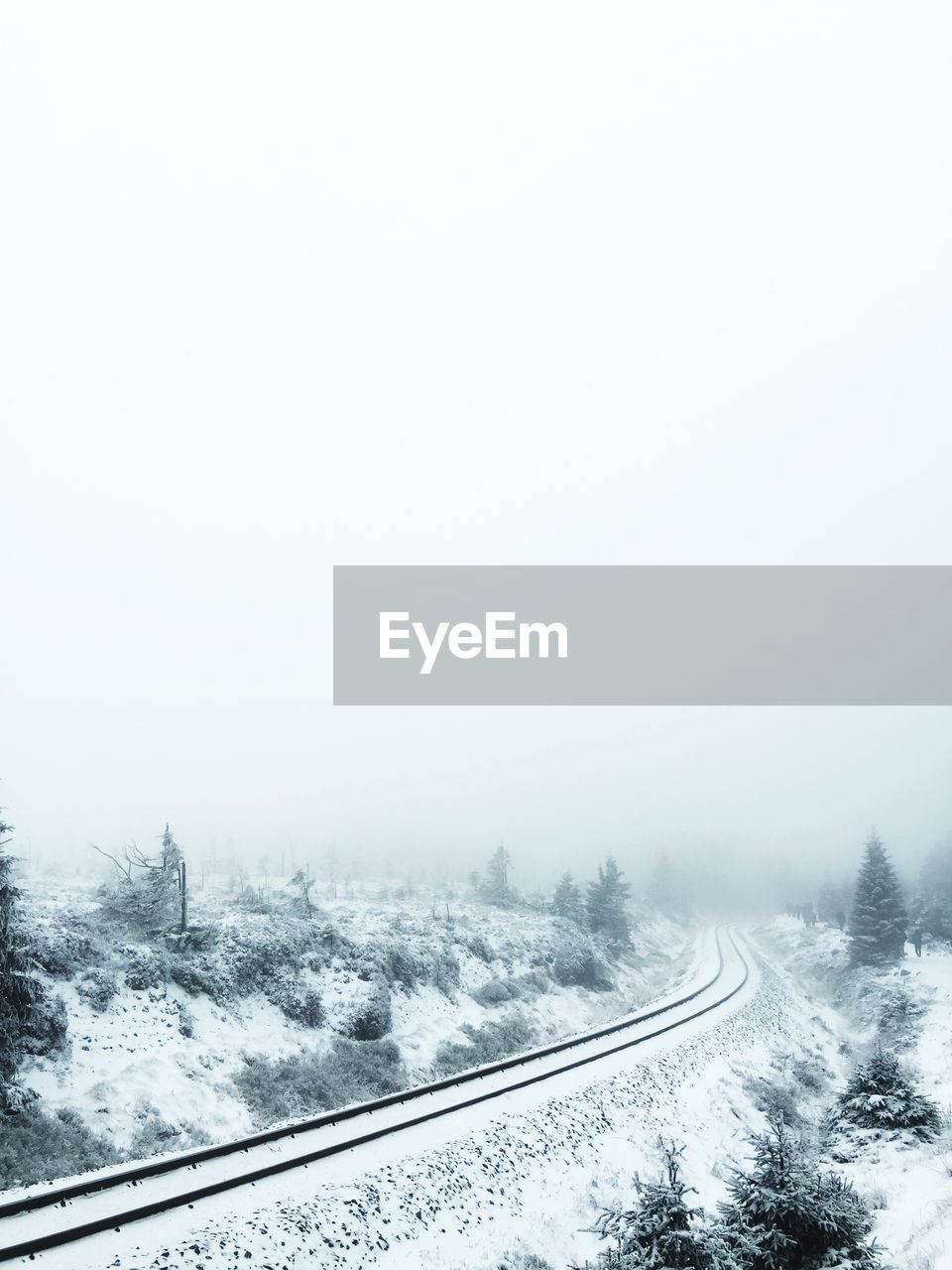 Snow covered railway tracks against clear sky