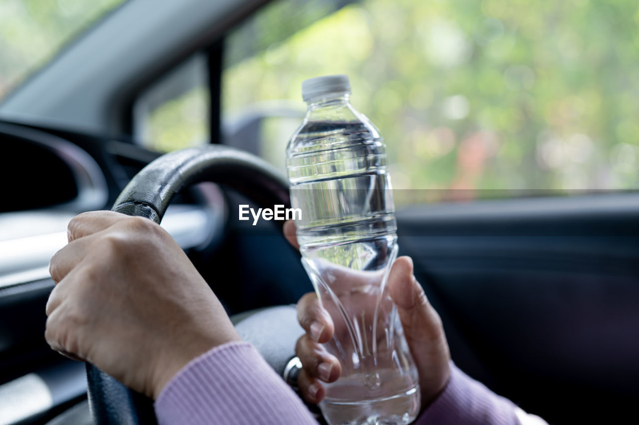 cropped image of man pouring water in car