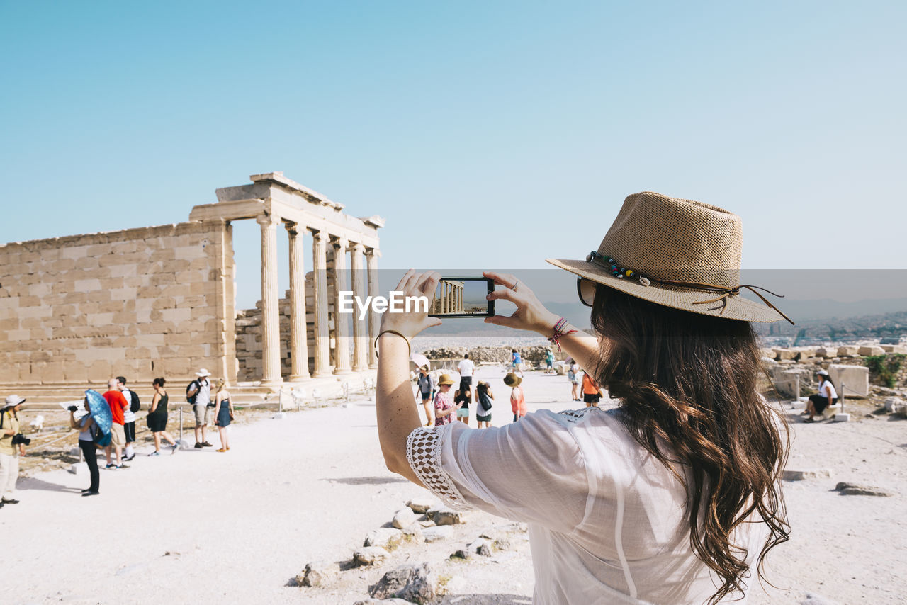 Greece, athens, woman taking a cell phone picture of the erechtheion temple in the acropolis