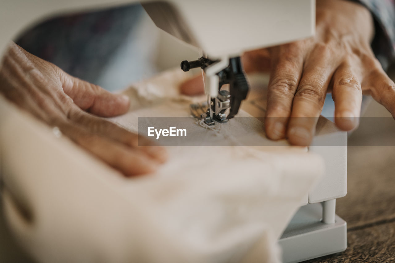 Woman sewing piece of fabric through sewing machine