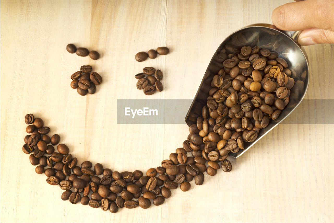 Cropped hand of person spilling coffee beans on table