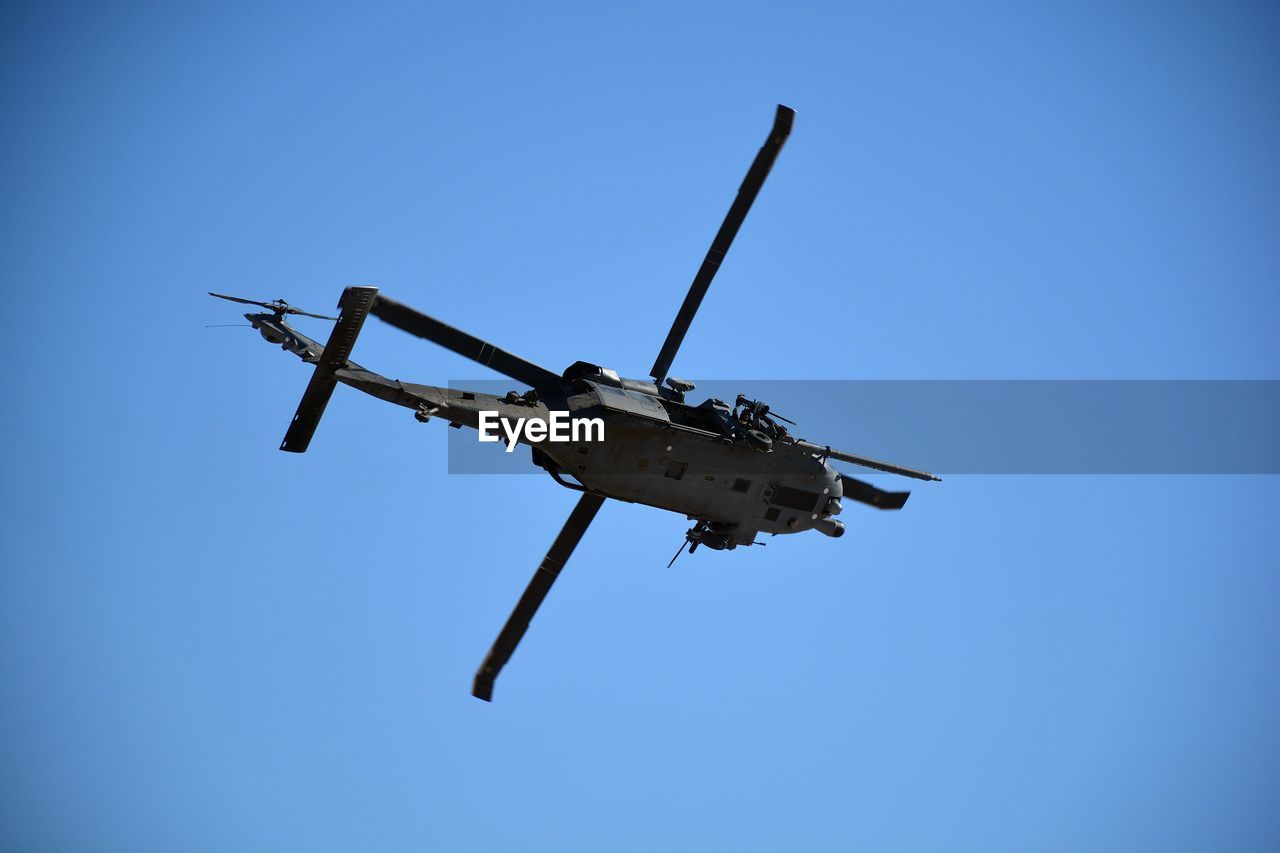 Low angle view of helicopter flying against clear blue sky