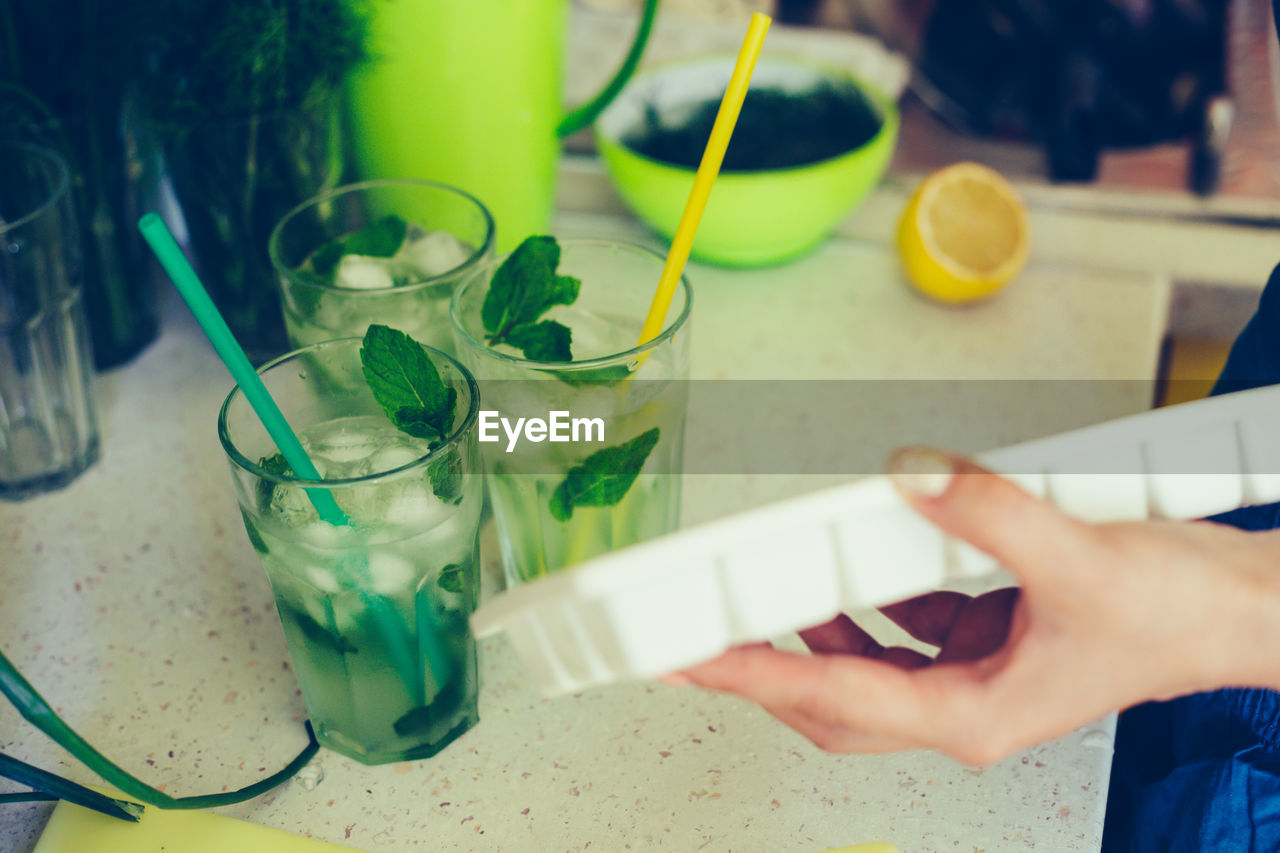 CROPPED IMAGE OF HAND HOLDING DRINK WITH TABLE