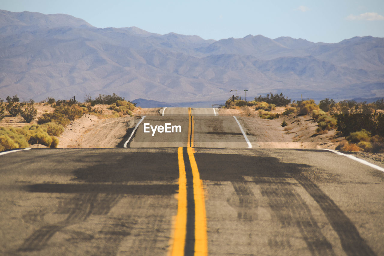 Road by mountains against sky