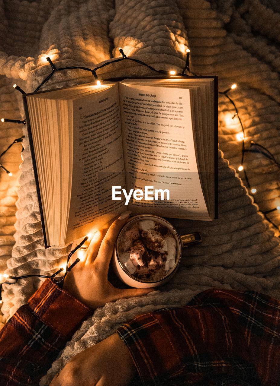 Christmas decorations with lights, hot drink, fruits and a good book