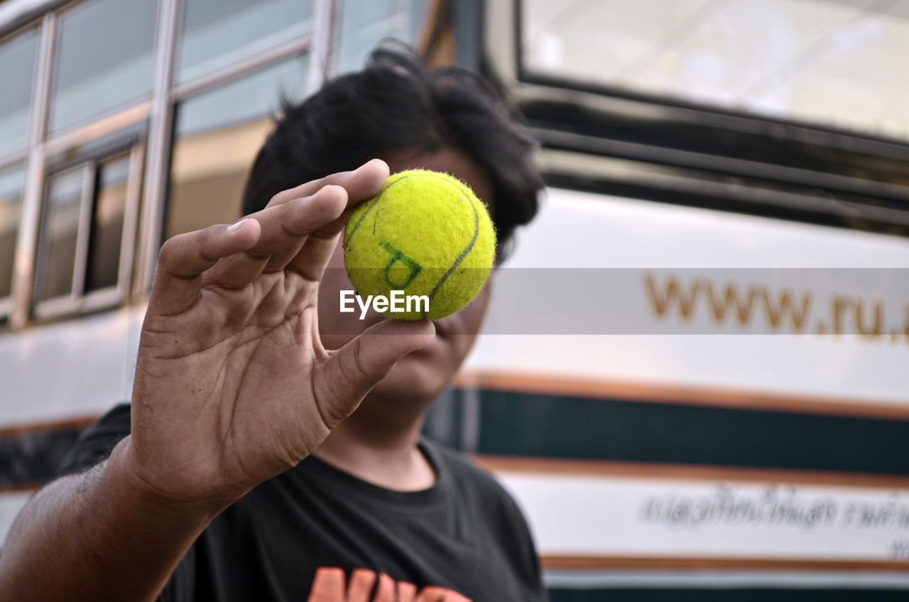 Close-up of man holding tennis ball in front of his face