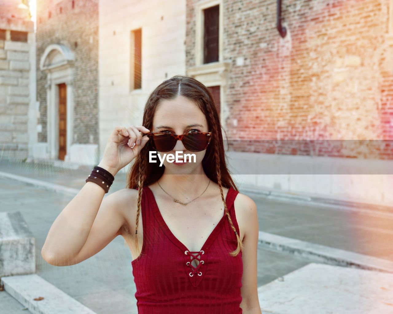 Portrait of woman wearing sunglasses standing outside building