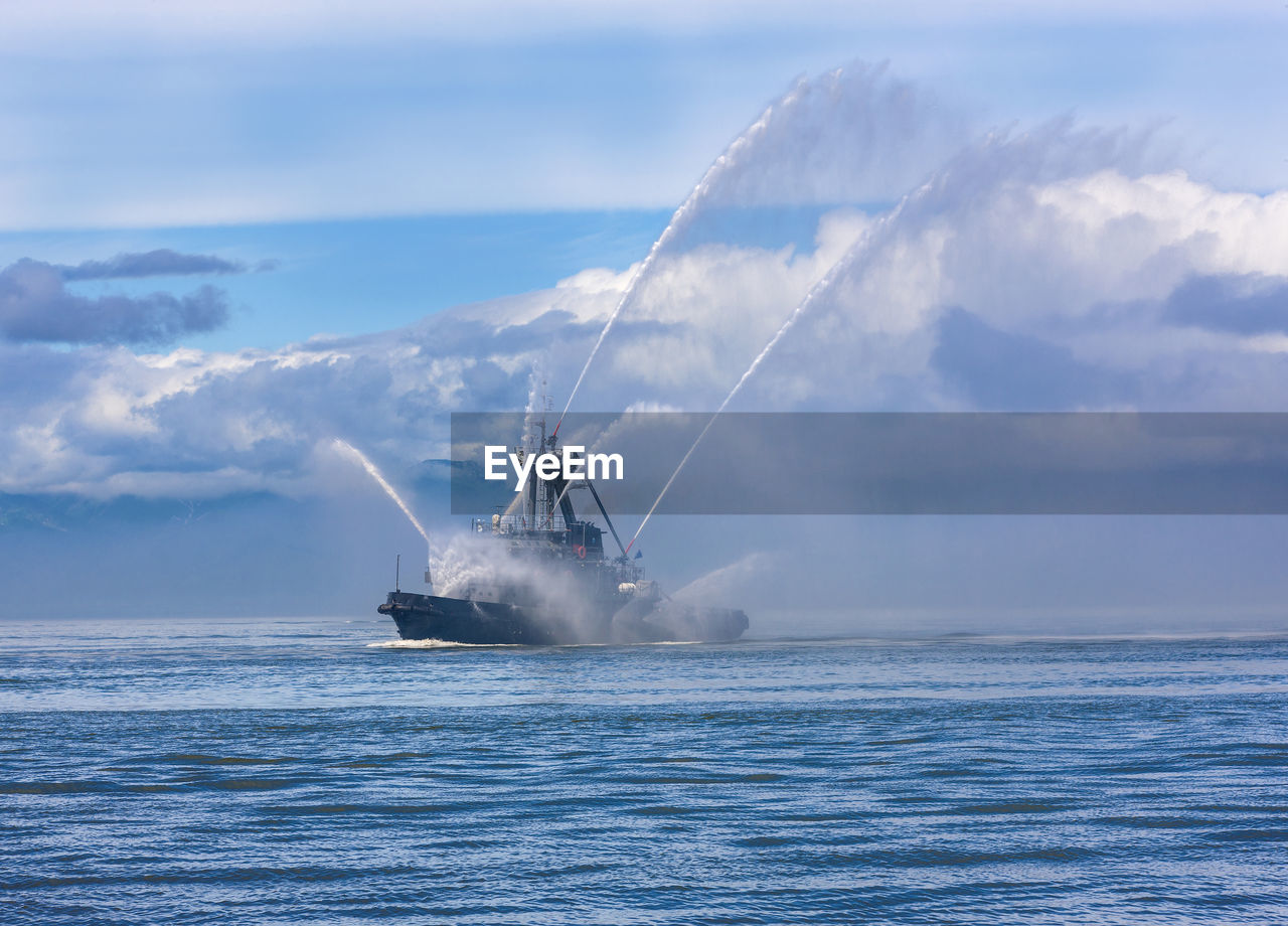 Fire hose boat spraying water on kamchatka on paciic ocean