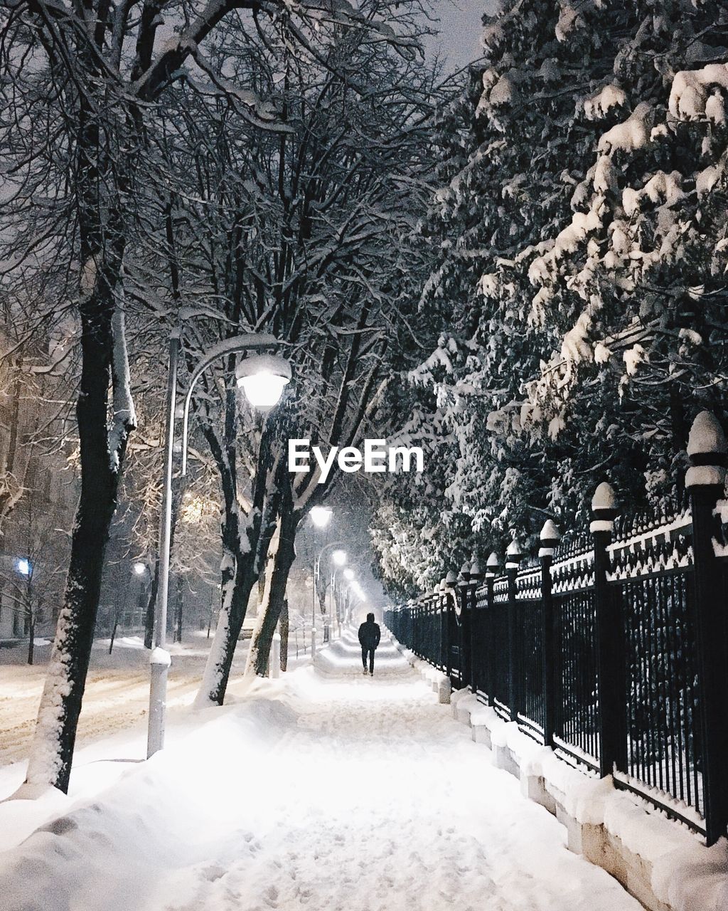 Man walking on snow covered footpath in city