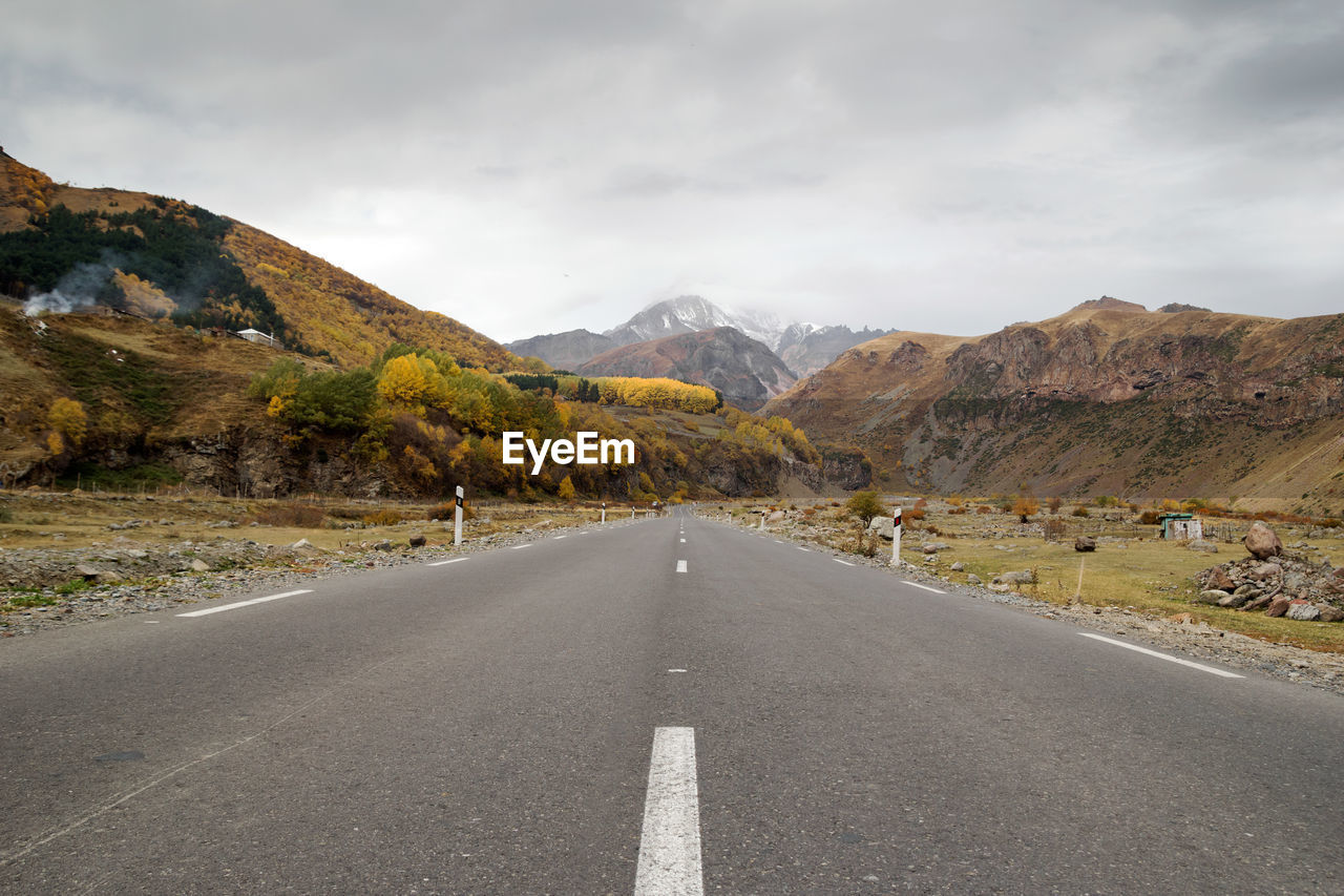 EMPTY ROAD ALONG MOUNTAIN RANGE AGAINST SKY