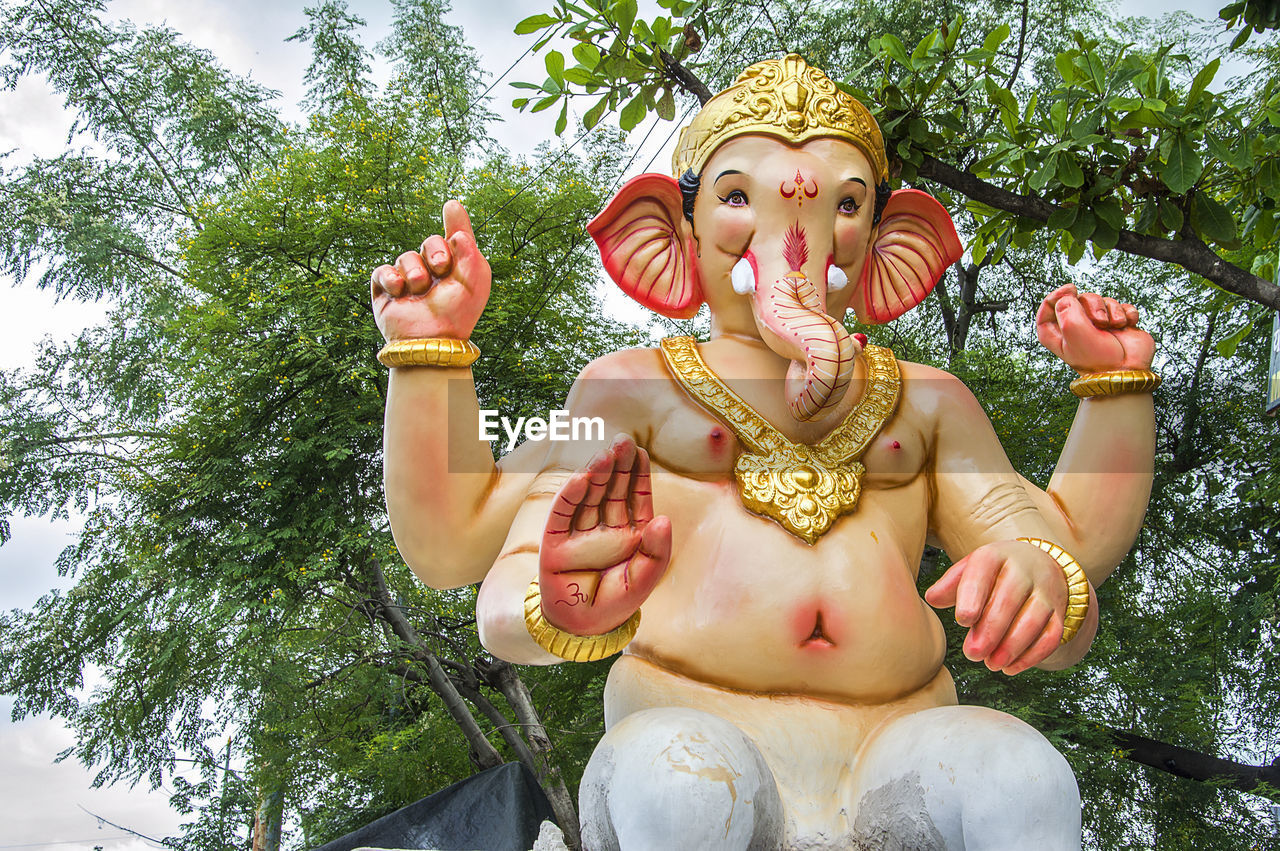 Low angle view of ganesha statue against trees