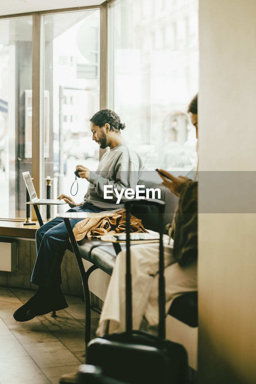 Full length of man using laptop while sitting in restaurant