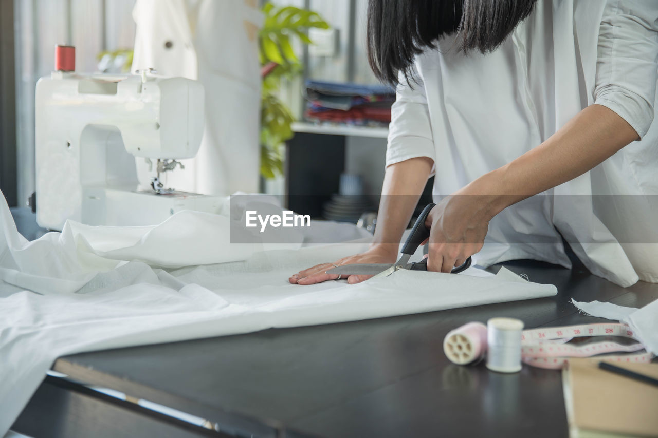 Midsection of woman cutting fabric on table