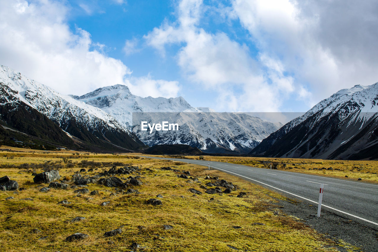 On the asphalt road to the big and tall mountains in winter, blue skies in new zealand