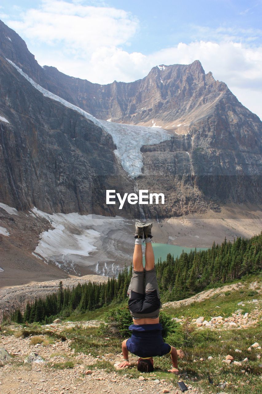 Rear view of man doing handstand on field