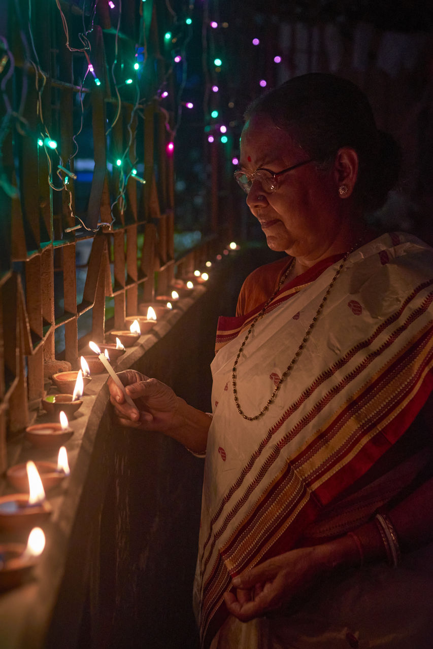 A hindu woman decorating her home with diyas on the evening of diwali and kali puja.