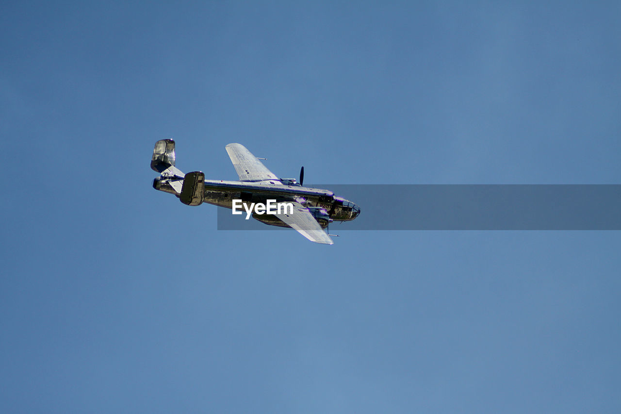 Low angle view of airplane flying against clear blue sky