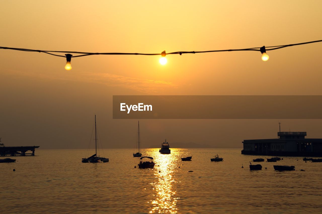 SILHOUETTE BOATS IN SEA AGAINST ORANGE SKY