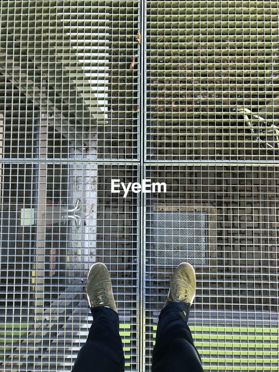 Low section of man standing on metal grate