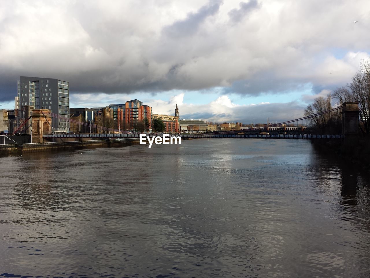 Suspension bridge over river clyde in city against sky