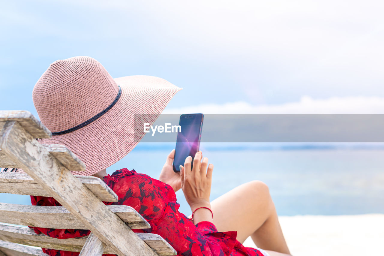 MIDSECTION OF WOMAN HOLDING UMBRELLA ON BEACH