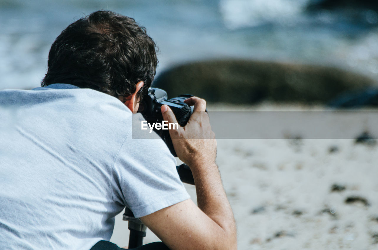 Rear view of man photographing at beach
