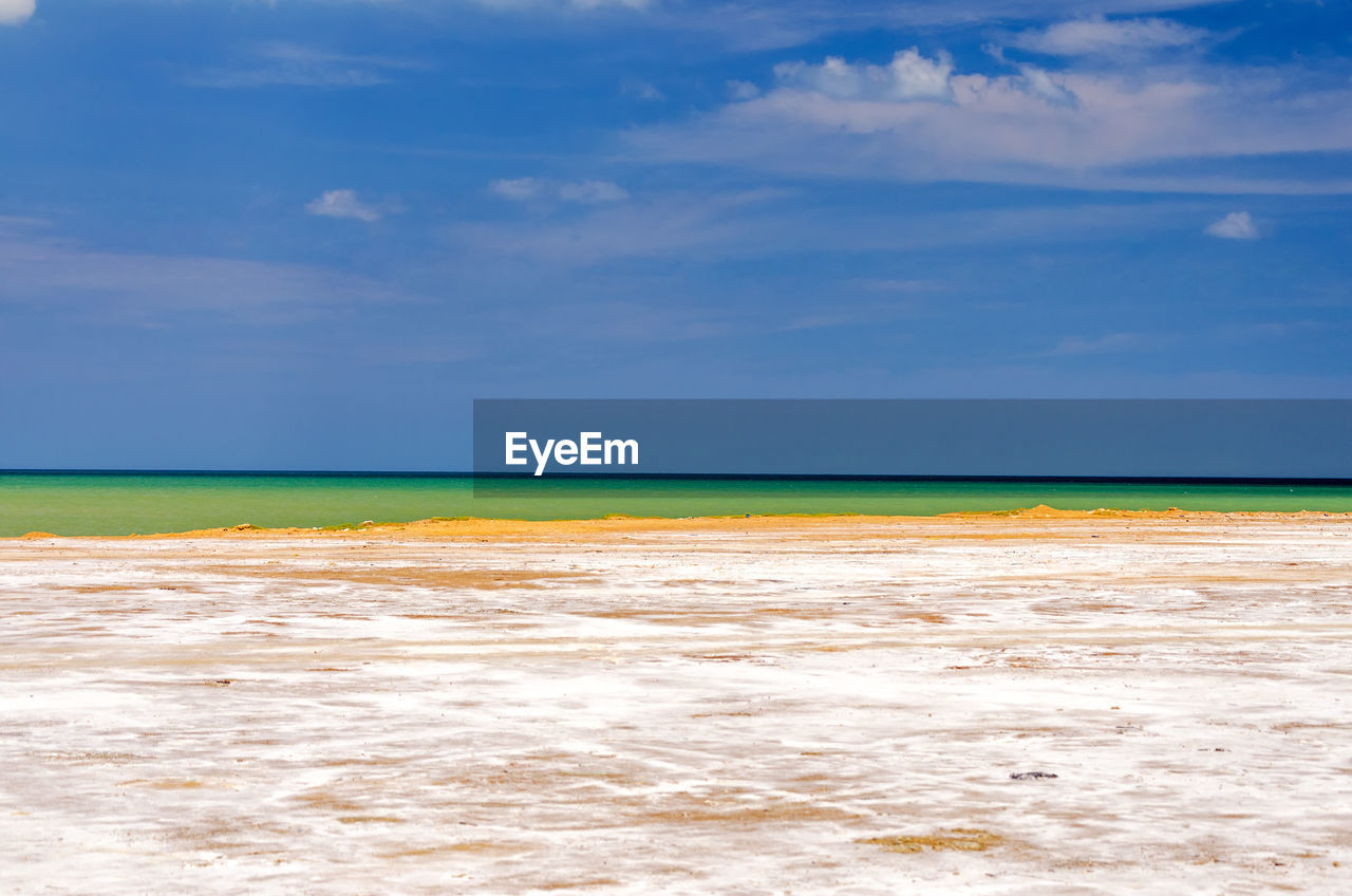 Salt flat by sea against blue sky