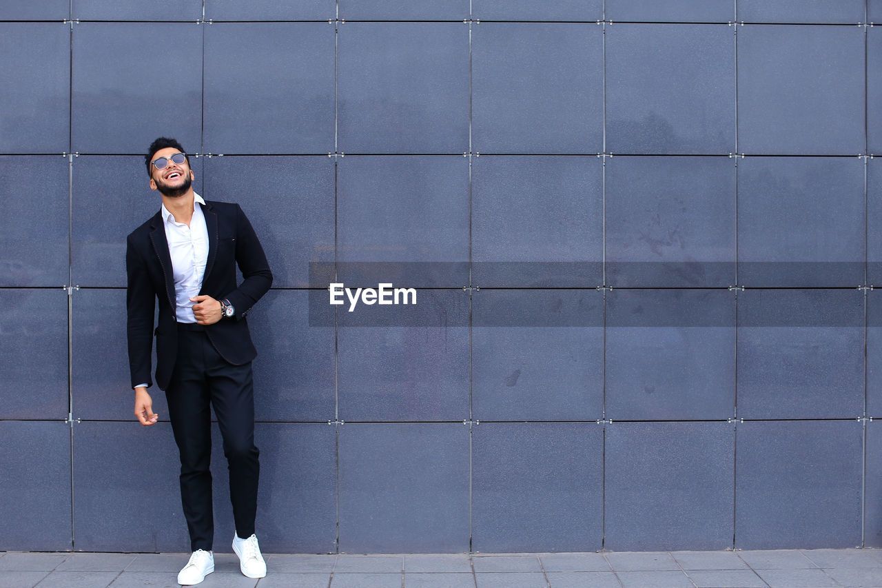 Full length of young man standing against wall