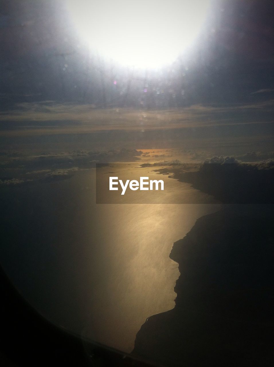 Scenic view of sun shining over sea seen through airplane window