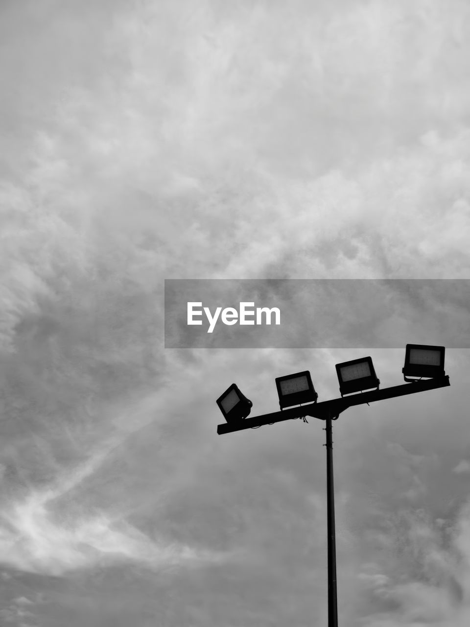 sky, cloud, low angle view, black and white, monochrome, no people, nature, monochrome photography, street light, communication, outdoors, black, lighting equipment, overcast, white, sign, pole, cloudscape, day, guidance, street, wind, line