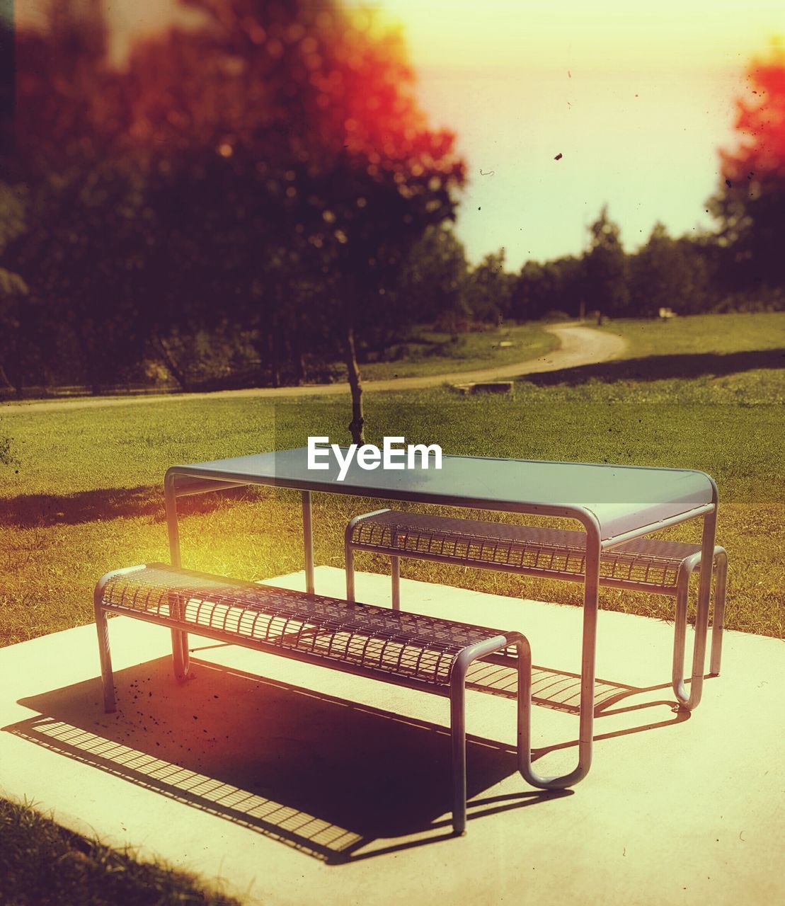EMPTY BENCH WITH CHAIRS IN BACKGROUND