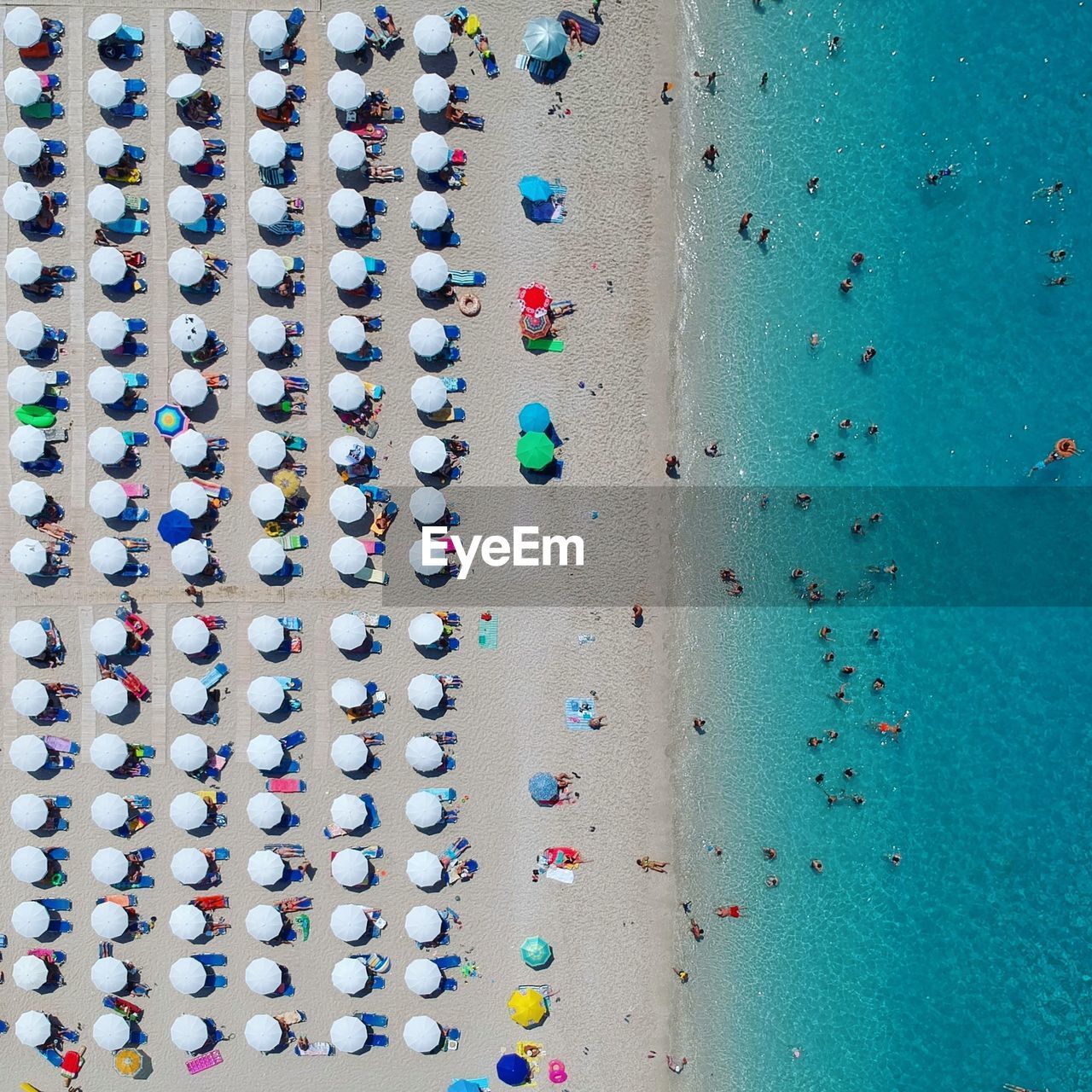 Directly above shot of parasols and people at beach during sunny day