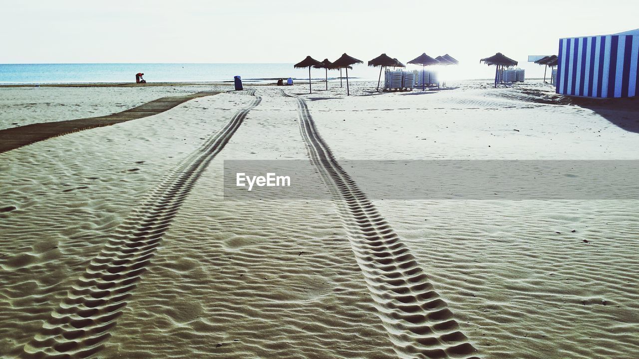 Tire tracks on beach during sunny day