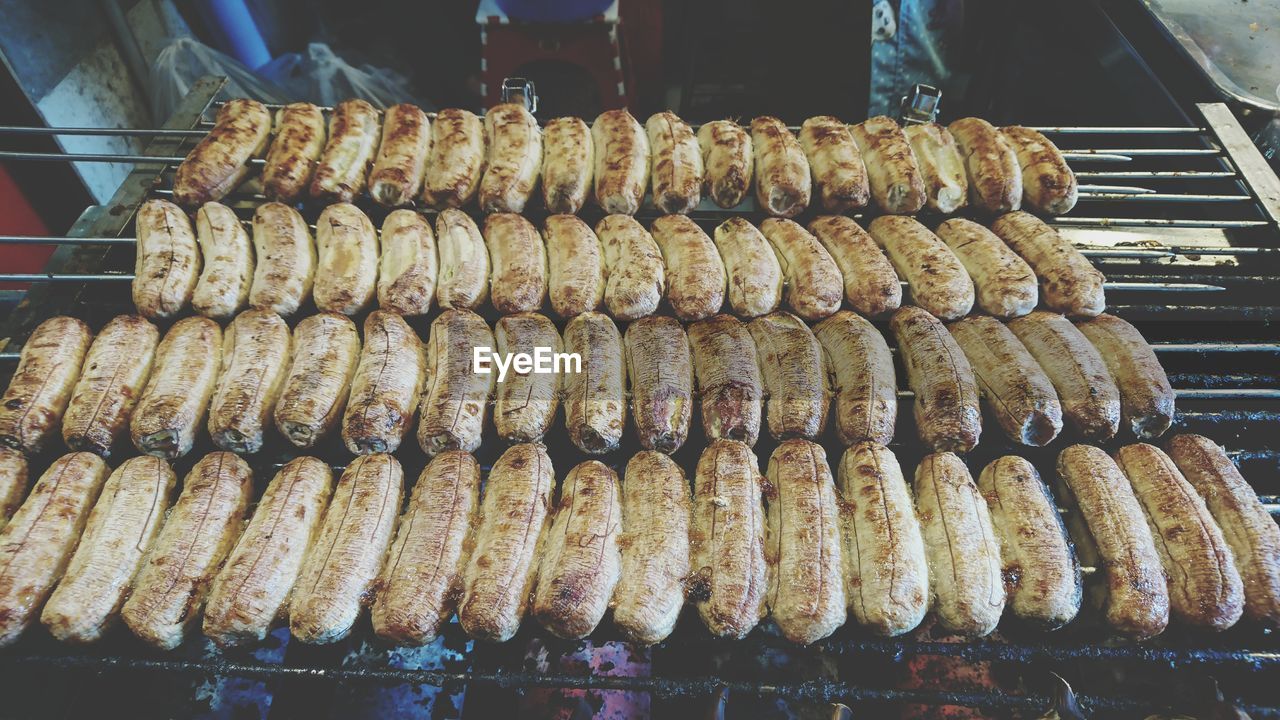 CLOSE-UP OF MEAT ON BARBECUE GRILL AT NIGHT