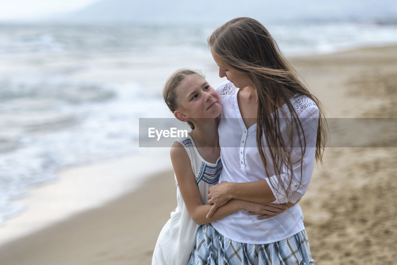 Mother with daughter standing at beach