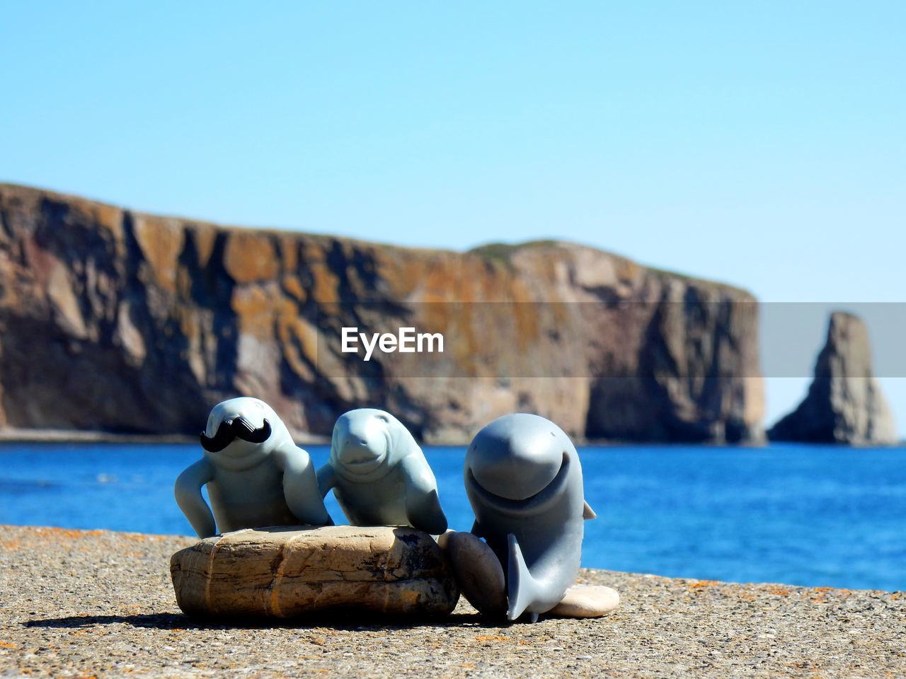 ROCKS BY SEA AGAINST BLUE SKY