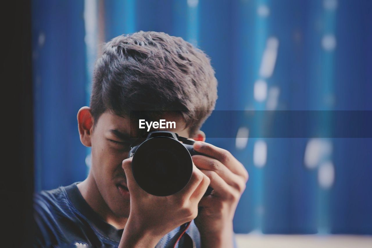 Close-up of young man photographing with camera