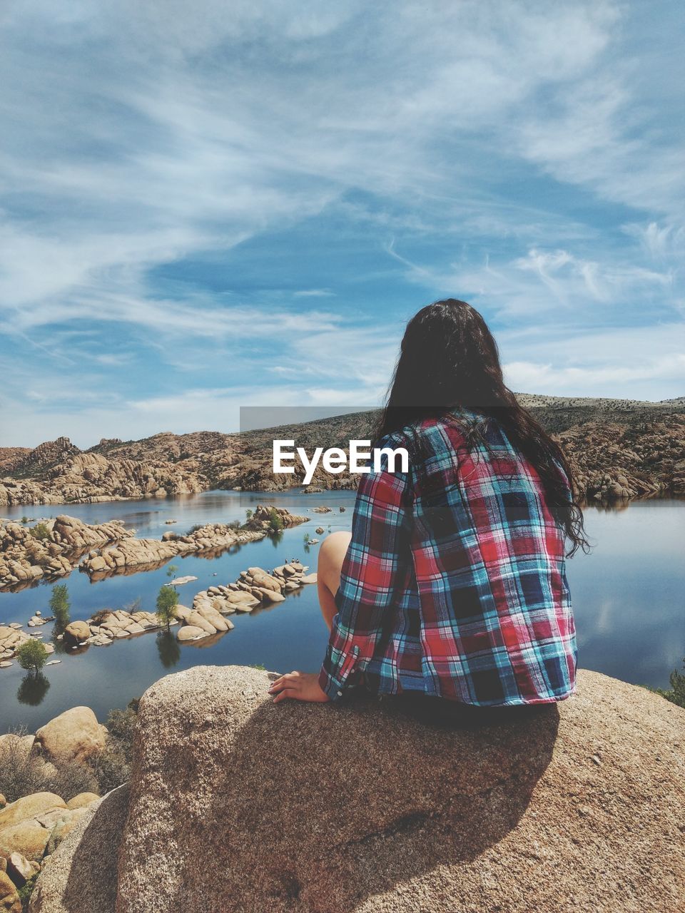 Rear view of woman sitting on a rock