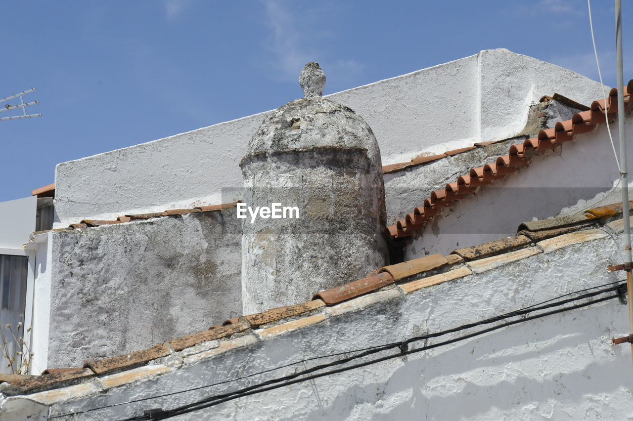 Low angle view of chimney on roofs against sky