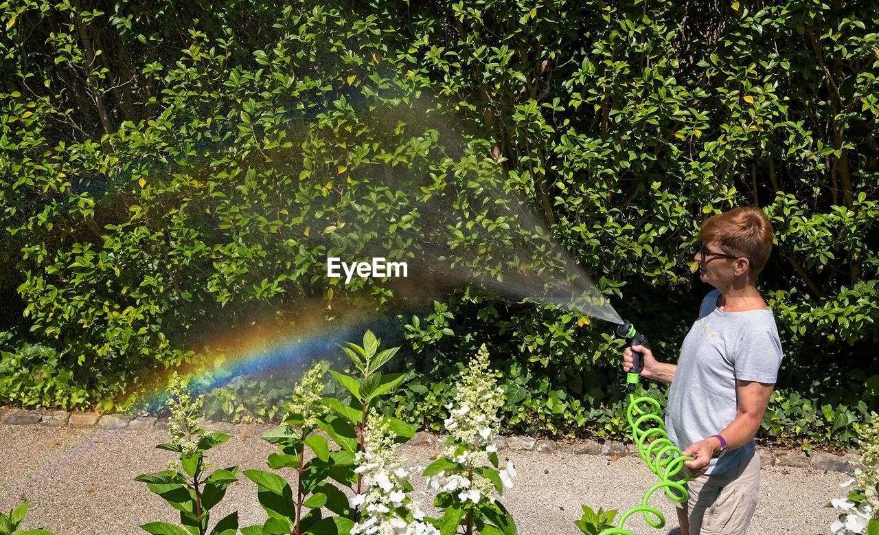 Woman watering the plants and rainbow appearing