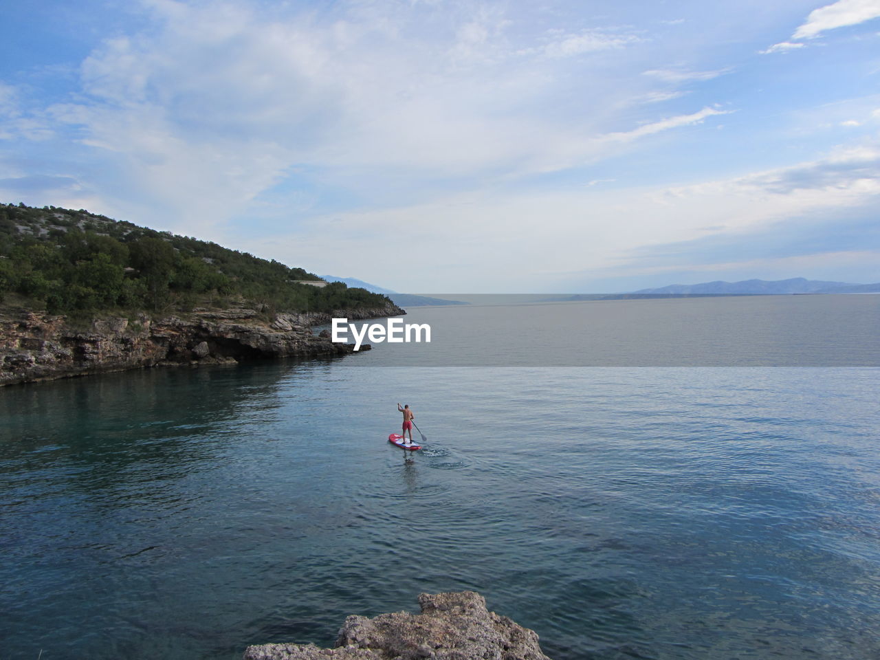 Man paddleboarding in sea against sky